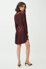Woman standing, looking over shoulder, wearing a dress and heels.