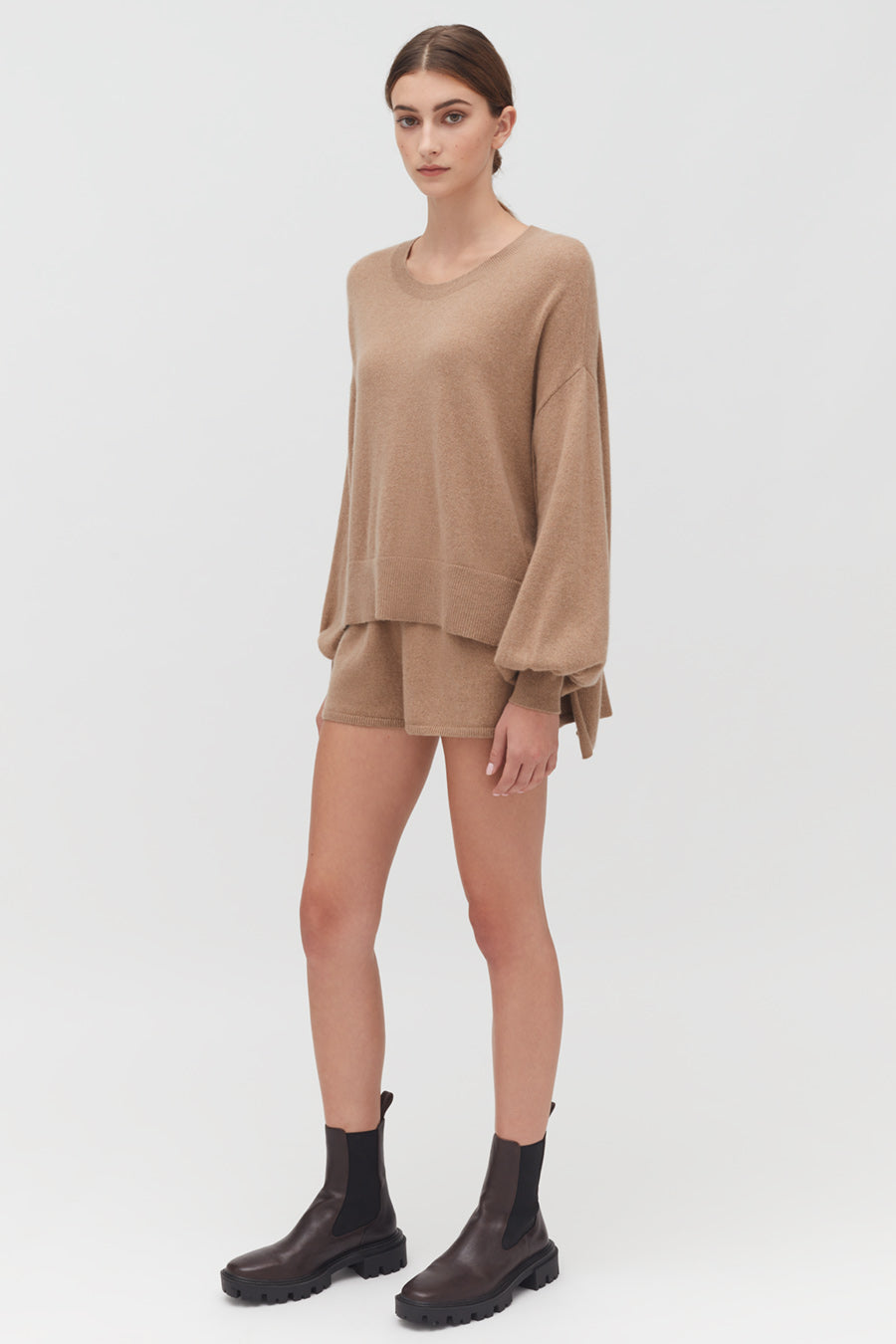 Single-Origin Cashmere Shorts Woman standing in a relaxed pose wearing a loose top, shorts, and boots.