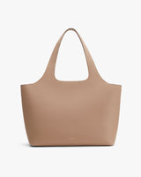 Leather tote bag with handle standing upright.