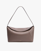 Handbag with a curved flap and a shoulder strap.