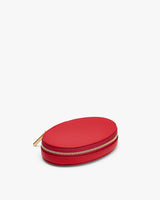 Oval-shaped small zippered case placed on a white surface.