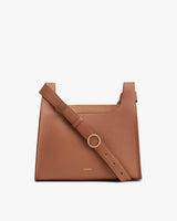 Handbag with a shoulder strap and front metal ring detail.