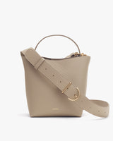 Handbag with a shoulder strap and metal buckle on a plain background.