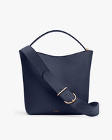 Handbag with a wide strap and curved handle on top.