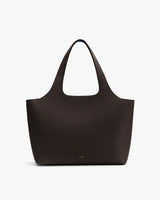Handbag with two handles and pebbled leather surface on plain background
