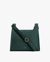 A handbag with an adjustable shoulder strap and a ring detail on the front.