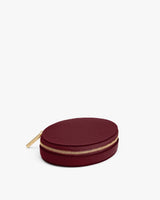 Round leather zippered case with gold-toned zipper on white background.