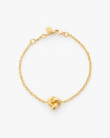 Chain bracelet with a knot detail on a plain background.