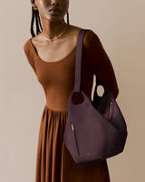 Person wearing dress and holding large handbag.