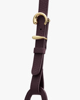 Close-up of a pebbled leather strap with gold buckle accents.