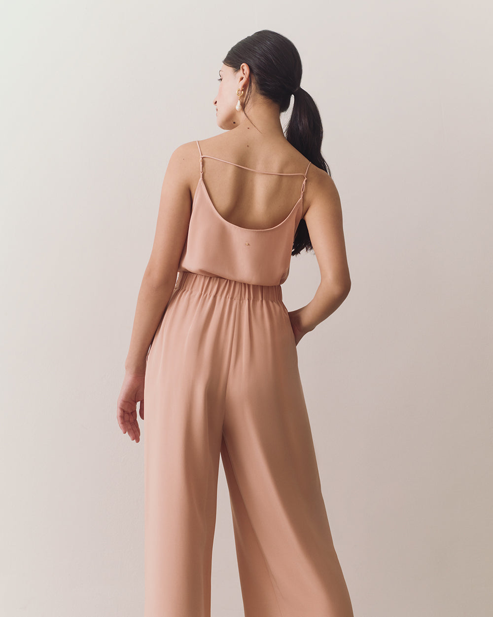 Person in sleeveless top and wide-leg pants, facing away.