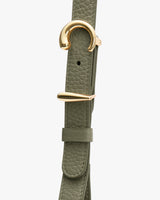 Close-up of a belt with a textured strap and gold buckle.