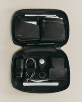 Open organizer containing various items like cables, a wallet, and pens.