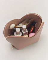 Open cosmetic bag filled with various makeup products.