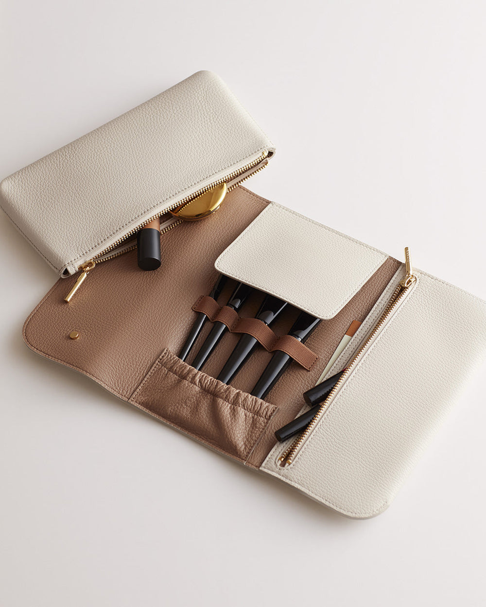 Makeup bag open showing cosmetics and brushes inside.