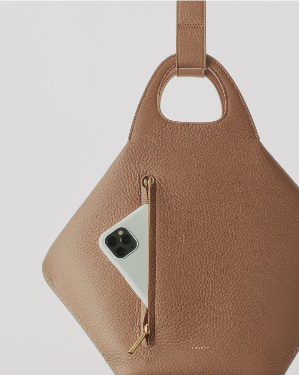 Textured bag with a zipper pocket, holding a smartphone, and a central handle cutout