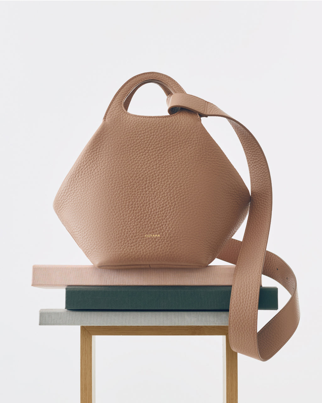 Textured handbag on stacked books and a wooden table