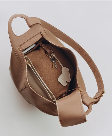 Open top view of a handbag with keys, a tablet, and a small wallet inside.