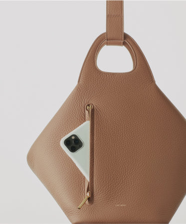 Leather handbag with front zipper pocket and smartphone partially tucked inside