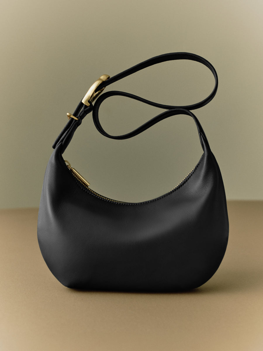 Shoulder bag with curved shape and metal accents.