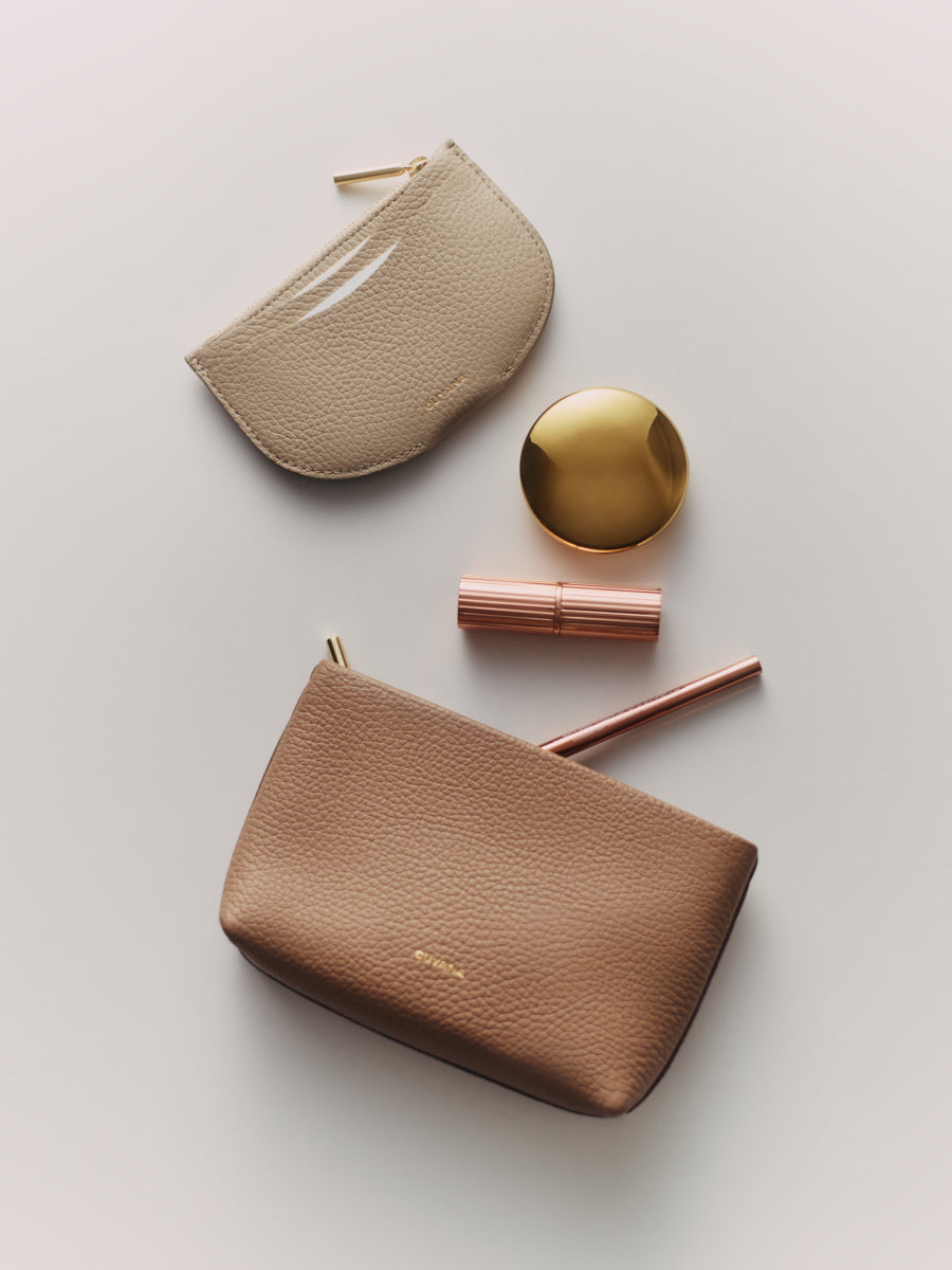 Two small pouches with makeup items scattered around them.