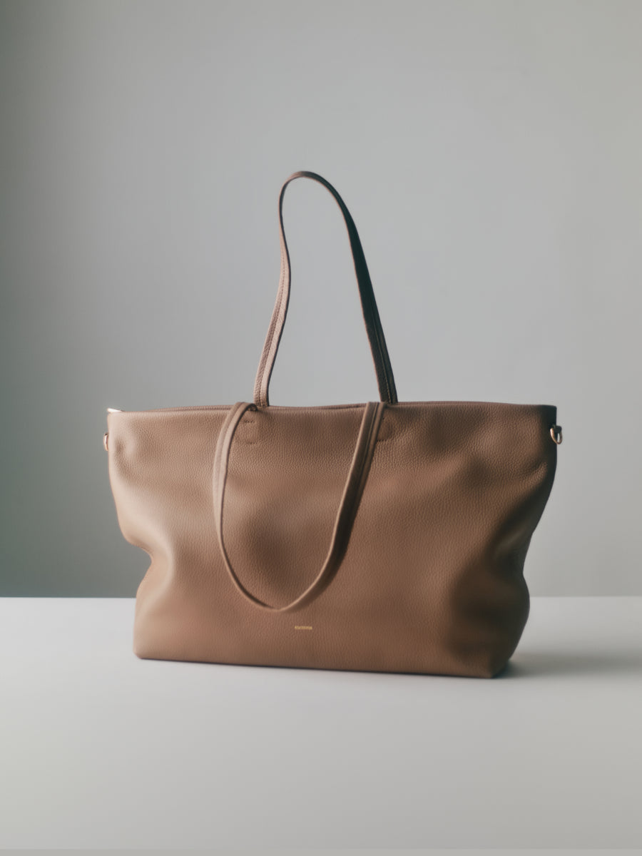 A large tote bag with long handles on a flat surface.