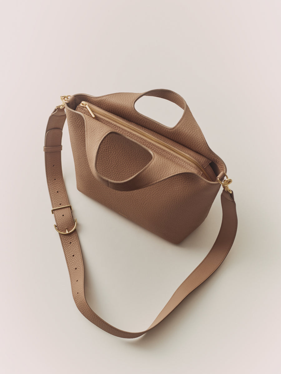 Handbag with a long strap and zippered top.