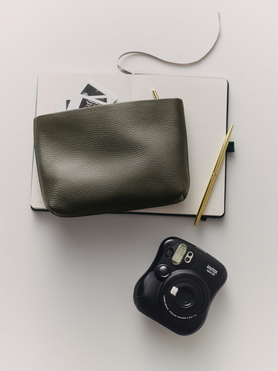 Notebook with pouch, pen, and camera on a table