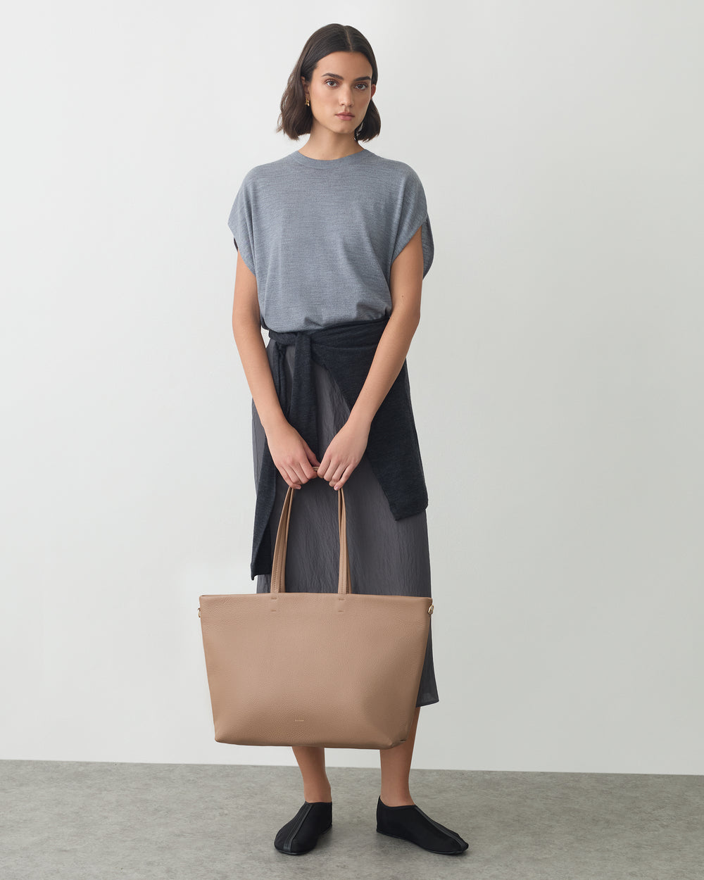 Classic Easy Zipper Tote A person holding a tote bag with a sweater tied at the waist.