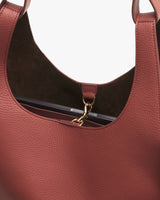 Open leather handbag with a gold clasp and a visible inner pocket.