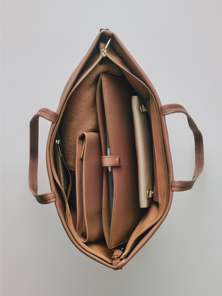 Open tote bag with multiple compartments and zippers from a top view.