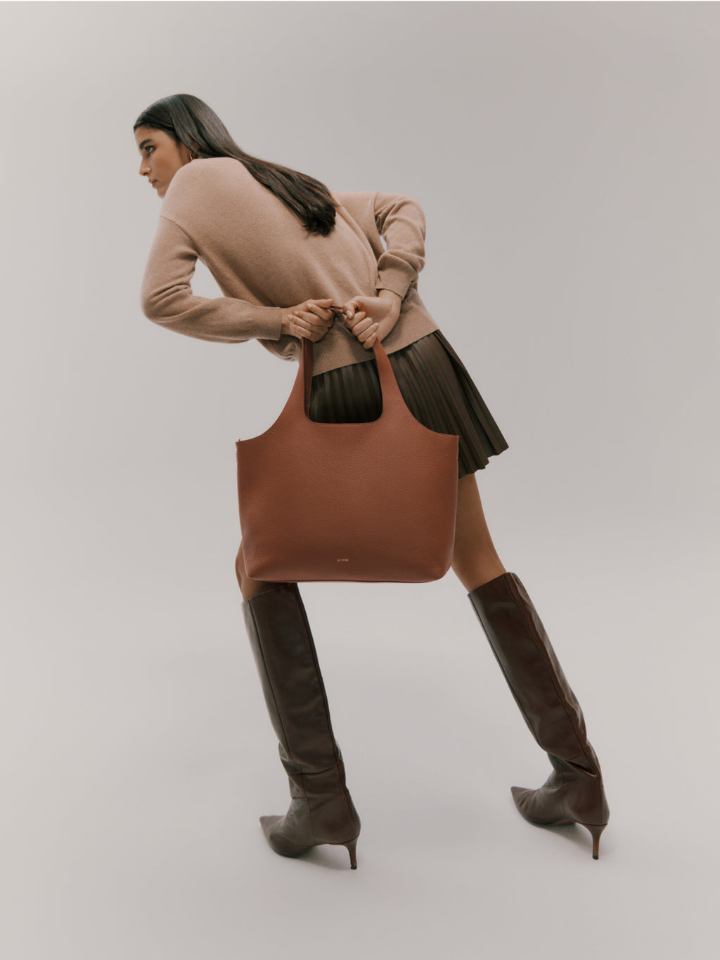 Woman walking and holding a large bag, looking away