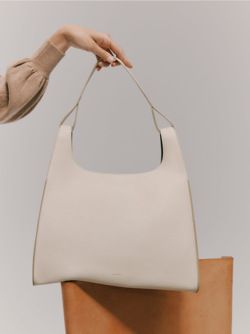 Person holding a handbag by the strap.