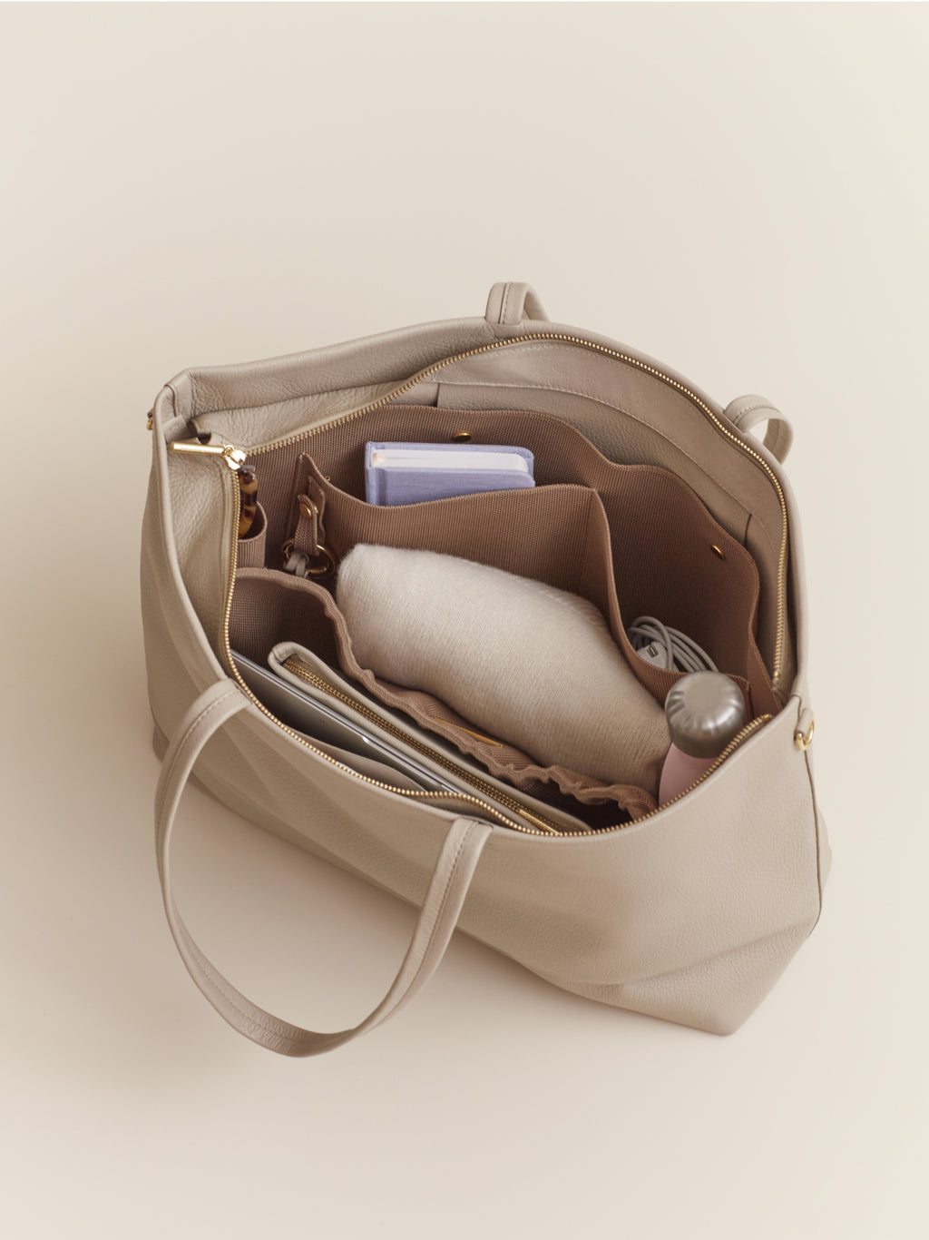 Open handbag showing internal compartments with various items like books and a wallet.