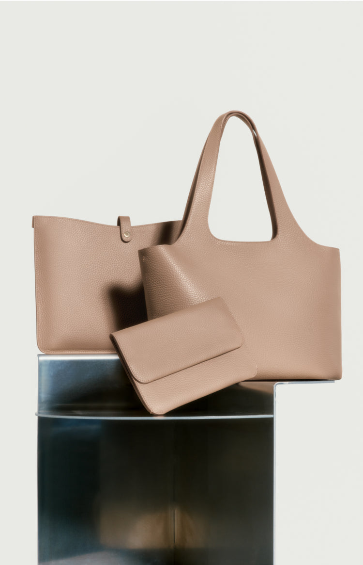 Three different sized bags displayed on a reflective surface.