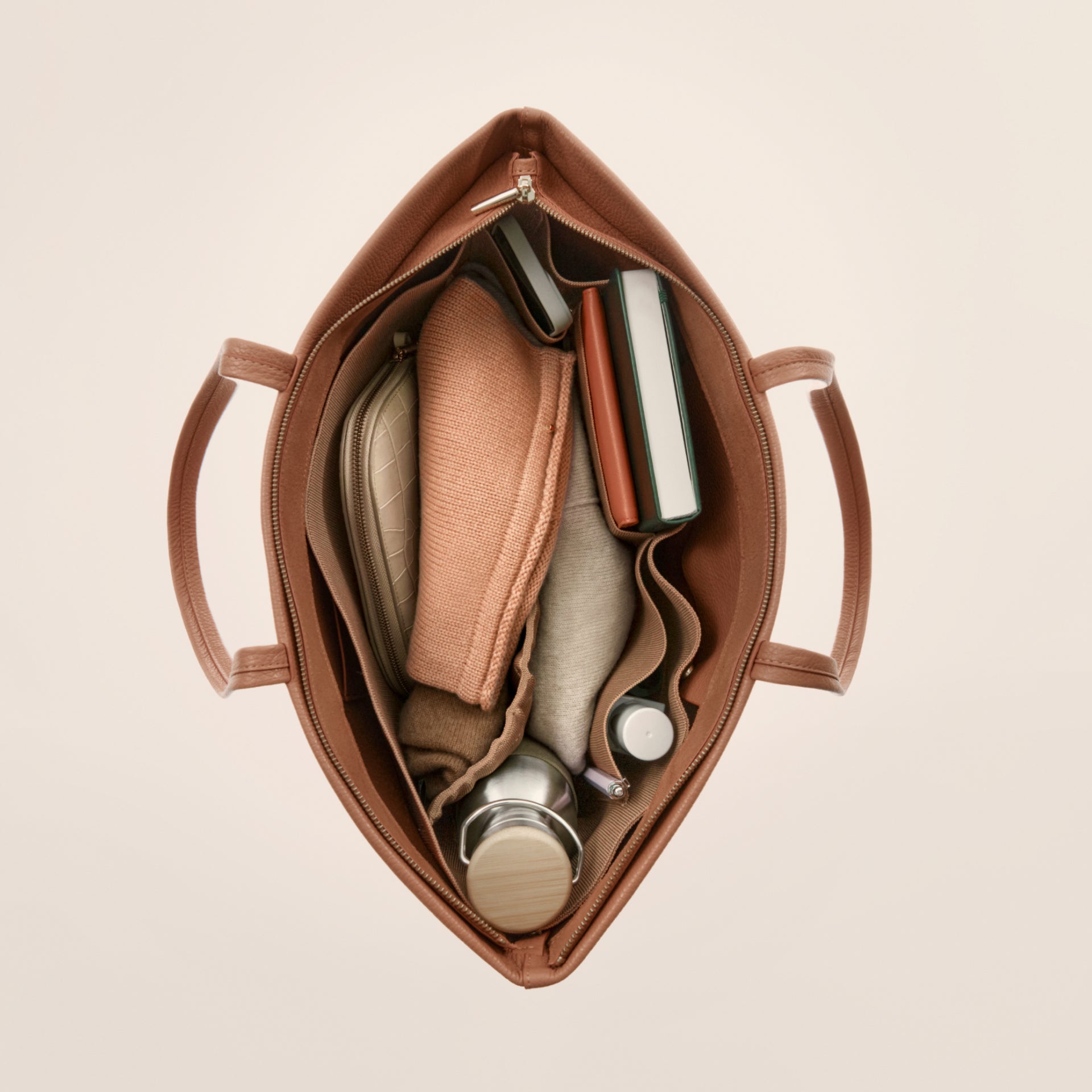 Overhead view of an open handbag with various items inside.
