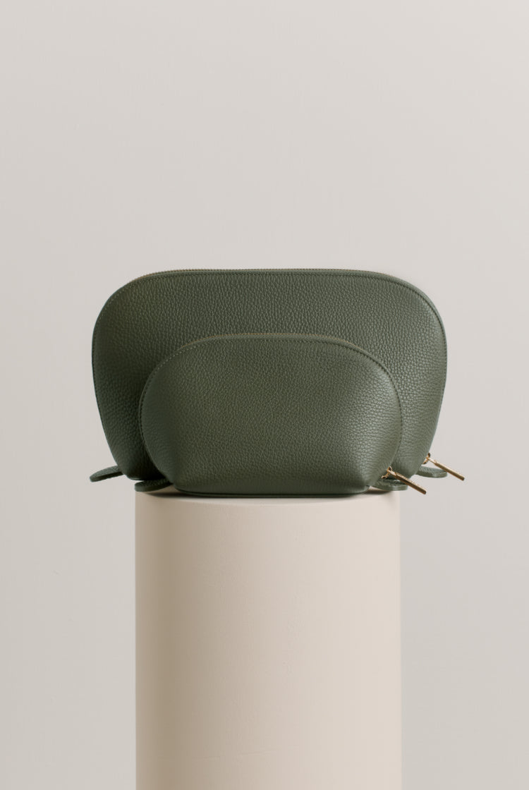 Leather handbag on a cylindrical pedestal.