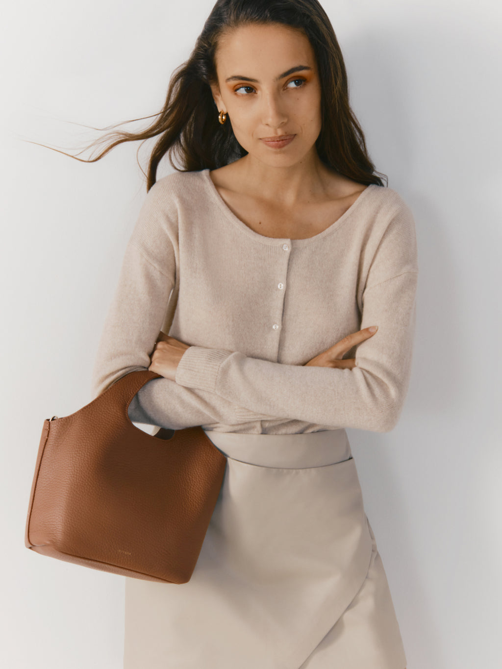 Woman standing with arms crossed holding a handbag