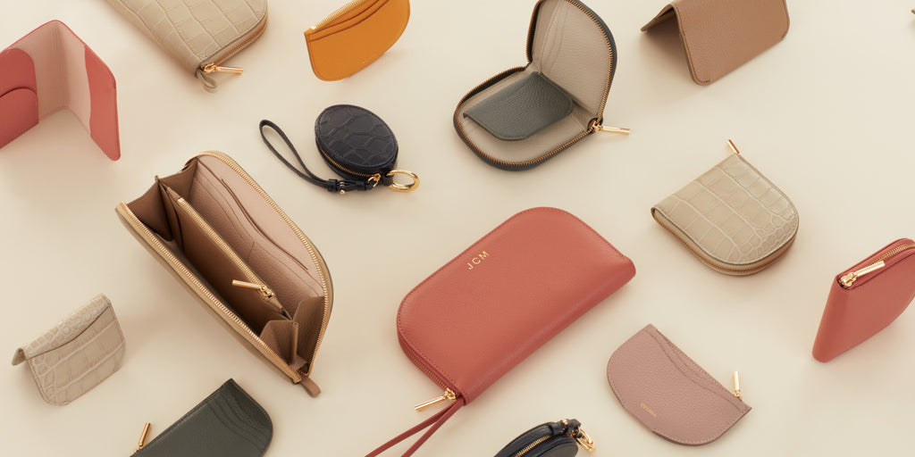 Various styles of small bags and wallets arranged on a surface.