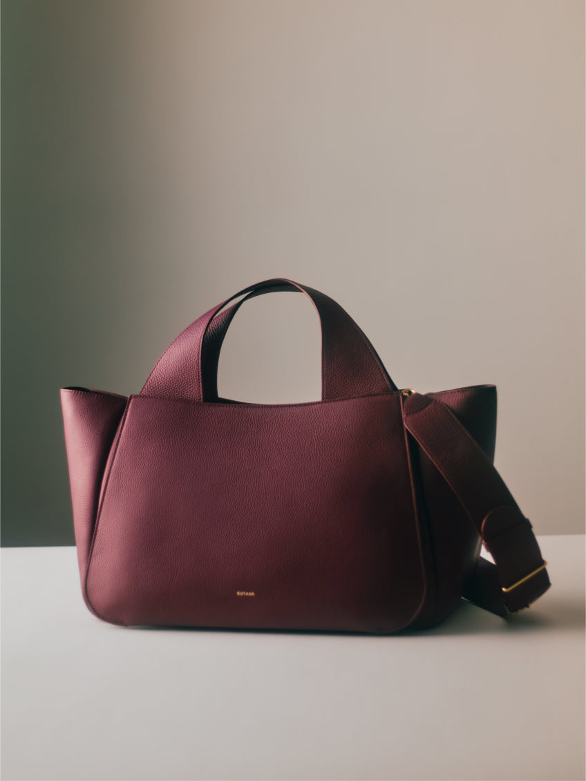 Handbag with a wide strap placed on a flat surface