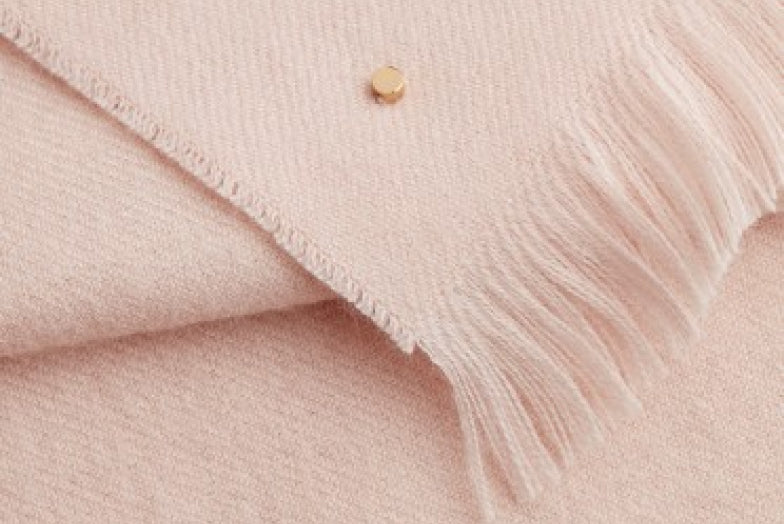 Close-up of a textured fabric with a small button and fringe detail.