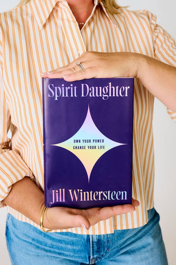 Spirit Daughter: Own Your Power, Change Your Life Person holding a book titled Spirit Daughter by Jill Wintersteen.