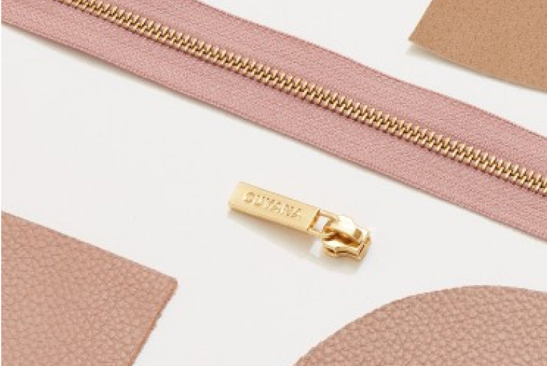 Zipper with slider detached and fabric patches arranged around it.