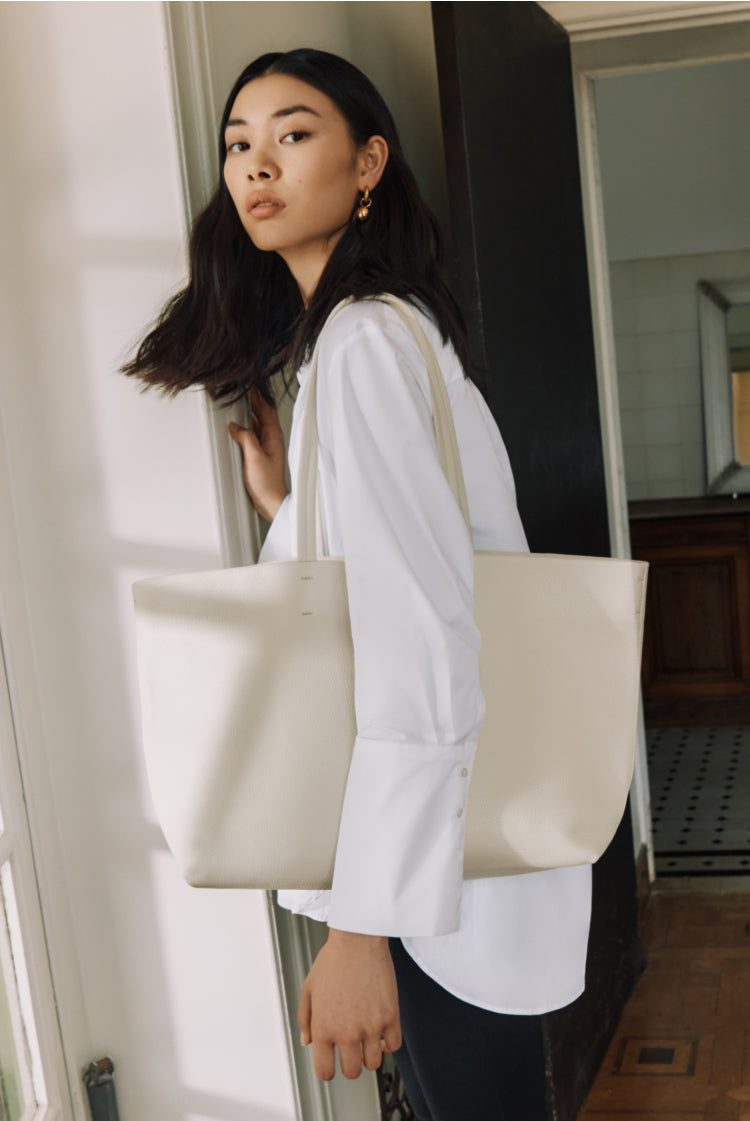 Woman holding a large bag standing by a door.