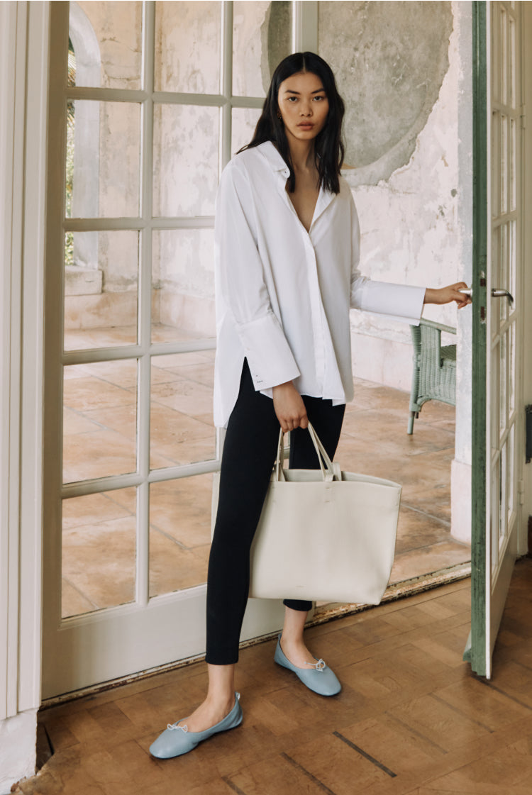 Woman holding a bag standing by an open door.