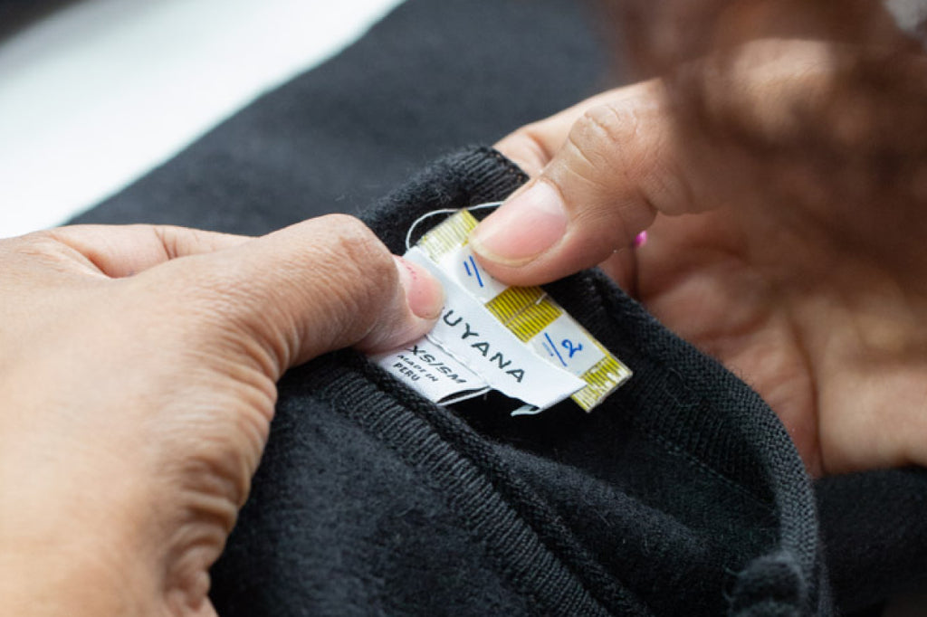 Hands attaching a tag to an item of clothing.
