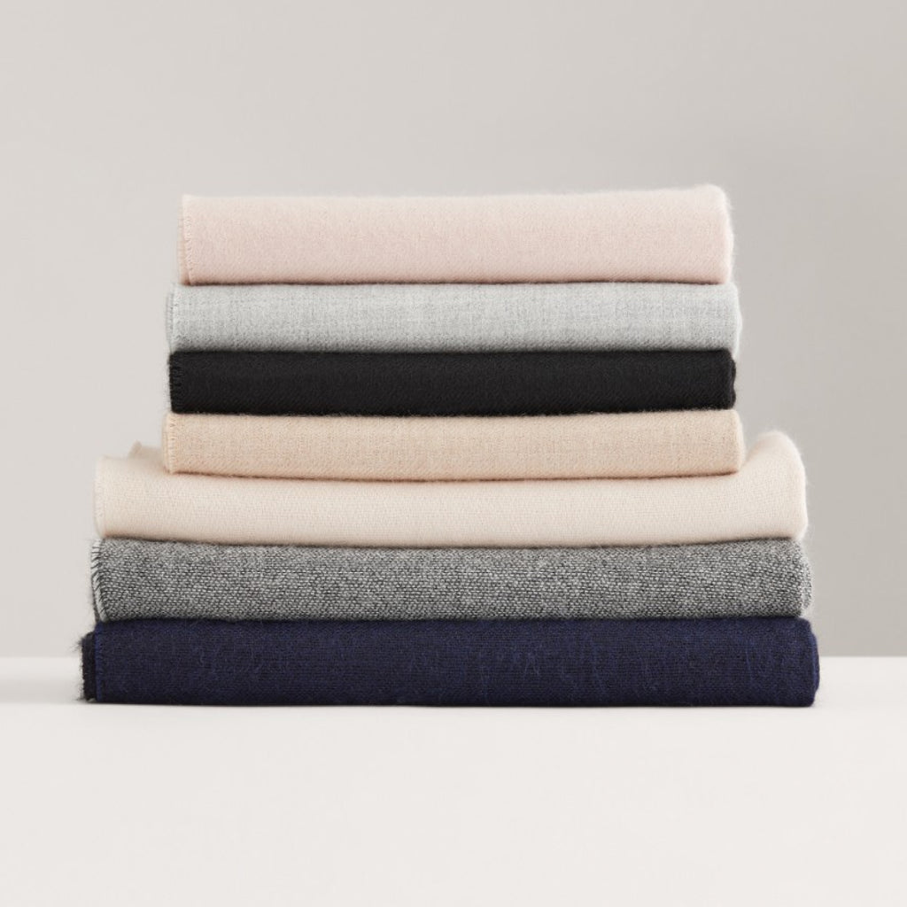 Stack of six folded sweaters on a flat surface.