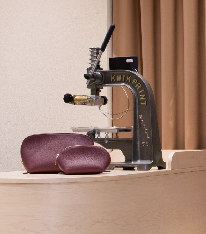 Eyeglass case next to a Kwikprint Model 55 machine on a desk