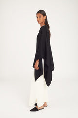 Woman in a long-sleeve top and wide-leg pants standing side view.