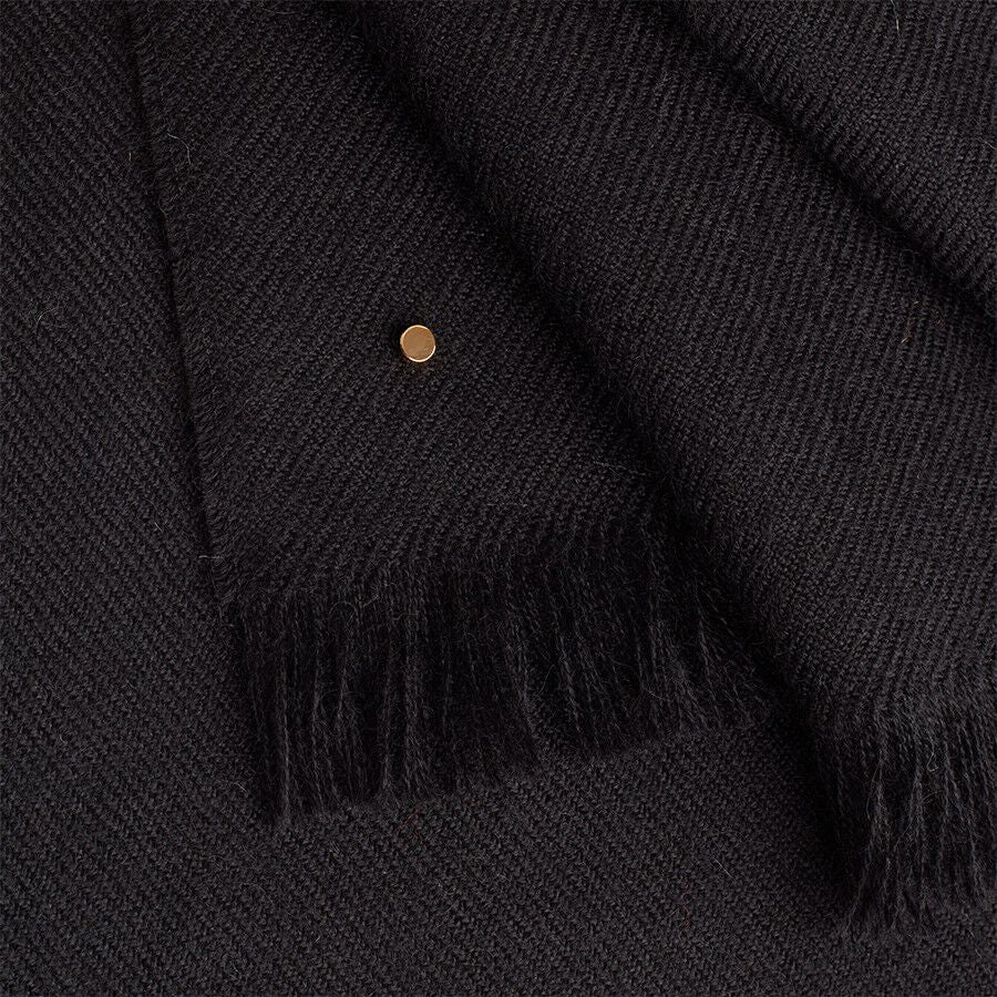 Close-up of a fringed fabric with a small circular embellishment.